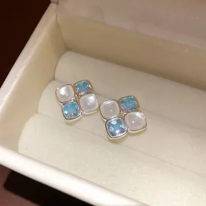 Detailed macro view of elegant square stud earrings with blue zircon and white resin