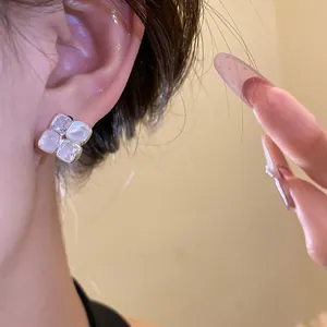 Close-up of elegant silver stud earrings with square zircon and resin stones on ear