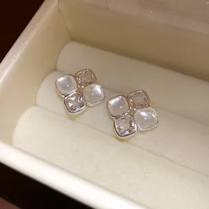 Detailed view of silver square stud earrings with zircon and resin in a jewelry box