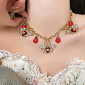 Close-up detail view of vintage ladybug and bee necklace with red enamel and crystals
