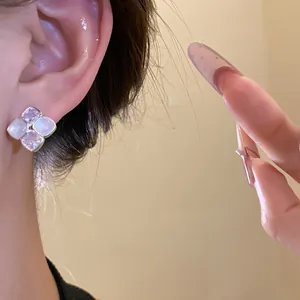 Detailed view of elegant zircon and resin clover stud earrings worn on the ear.
