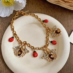 Detailed view of vintage gold necklace featuring enamel ladybug and crystal bee charms