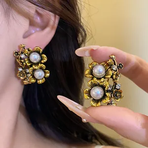 Close-up of vintage floral earrings with pearls and rhinestones in antique gold finish.