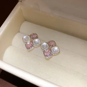 Close-up of vintage pink and white square cluster stud earrings in a cream jewelry box