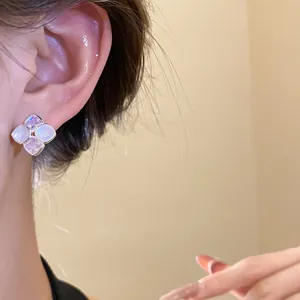 Close-up of elegant rhombus shaped zircon and resin stud earrings on a model ear