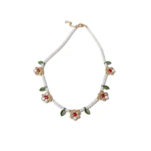 Collana di perle di vetro bohémien con ciondoli a fiore dorati e foglie verdi eleganti.