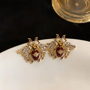 Vintage gold-tone bee stud earrings with red enamel and clear crystal wings detail