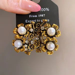 Close-up of vintage gold-tone flower earrings with large pearls and rhinestones.
