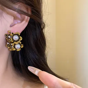 Close-up of vintage gold flower earrings with pearls and rhinestones on ear