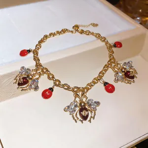 Close-up of vintage gold necklace with crystal bee and red enamel ladybug charms