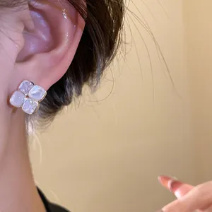Close-up of vintage square stud earrings featuring sparkling zircon and white resin
