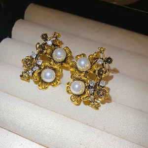 Detailed close-up of vintage floral stud earrings with pearls and rhinestones on velvet