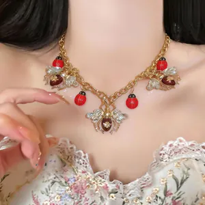 Close-up of vintage ladybug necklace with crystal wings and red enamel on a model's neck