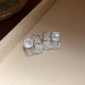 Close-up detail of silver zircon resin square stud earrings in a luxury display
