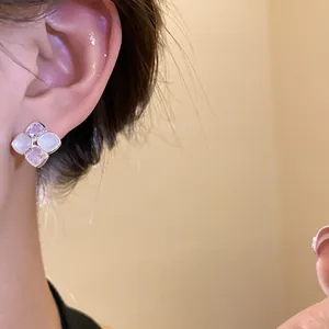 Close-up of elegant silver needle stud earrings with zircon and resin stones on model's ear