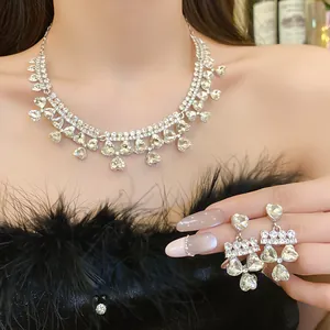 Detail of elegant rhinestone heart pendant necklace and matching earrings on a model.