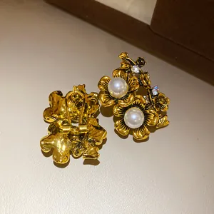 Close-up detail of vintage gold-finished flower earrings featuring pearls and crystals