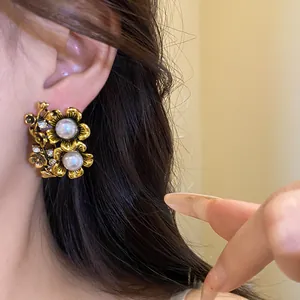 Close-up detail of vintage floral stud earrings with pearls and rhinestones on a model