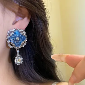Elegant vintage court style earrings featuring blue enamel flower and rhinestone teardrop pendants