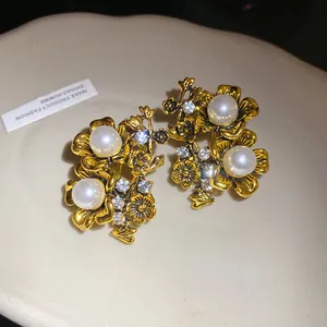 Close-up detail of vintage gold-tone floral earrings with pearls and rhinestones.