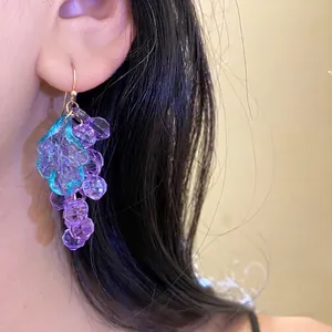 Elegant purple acrylic grape cluster earrings with teal leaf detail shown on model.