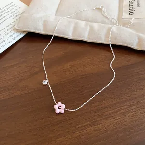 Close-up of a silver necklace with a pink flower pendant and clear zircon detail