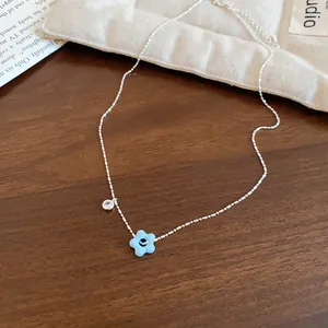 Close-up detail of silver clavicle chain featuring a blue flower and sparkling zircon charm.