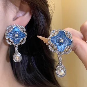 Detail showing vintage blue enamel earrings with crystals and elegant teardrop pendants.