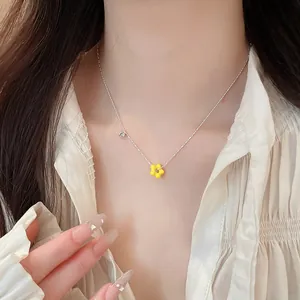 Close-up of elegant yellow flower pendant necklace on model wearing white ruffled shirt