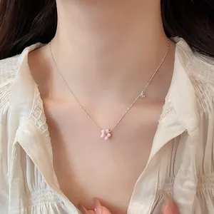 Detail showing a silver necklace with a pink flower pendant worn by an Asian model.