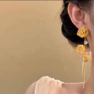 Close-up view of gold flower tassel earrings with zircons worn on a model for detail showcase