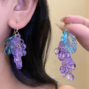 Detailed view of purple acrylic grape earrings with blue leaves and gold hooks