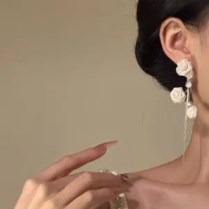 Élégantes boucles d'oreilles à pompon rose blanche avec des accents de zircon sur un modèle