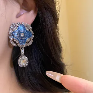Close-up of vintage palace style earrings with blue enamel and waterdrop crystal