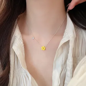 Close-up of a delicate silver necklace with a bright yellow flower pendant and zircon.