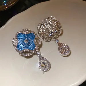 Detailed view of vintage blue enamel earrings with crystal accents and teardrop pendants