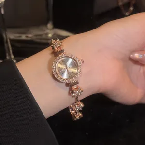 Close-up of a vintage rose gold bracelet watch with rhinestone flower links on a wrist.