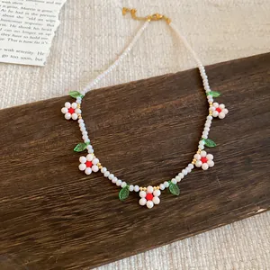 Dettaglio di una collana di perline bianche fatta a mano con ciondoli a fiori