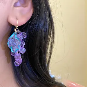 Detailed view of elegant purple acrylic grape cluster earrings worn on a person's ear
