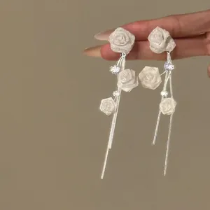 Vue détaillée de boucles d'oreilles élégantes en roses de tissu blanc avec zircone