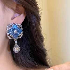 Macro detail of vintage palace style blue enamel earrings with sparkling teardrop crystal