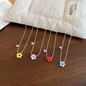 Close-up of four dainty zircon lucky flower necklaces in assorted vibrant colors