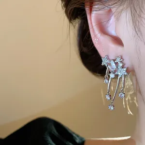 Primo piano di orecchini pendenti a stella con zirconi indossati da una modella asiatica.