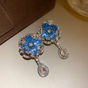 Detail of vintage palace style earrings with blue enamel and teardrop pendants