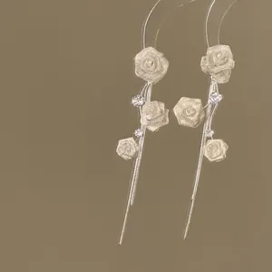 Vue détaillée de boucles d'oreilles pendantes argentées avec roses et zircons