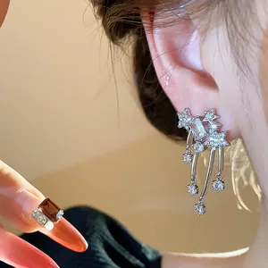 Primo piano di orecchini a stella in zircone e anello elegante indossati da una modella