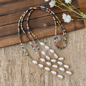Detailed view of a handmade colorful beaded necklace with teardrop pearls on rustic wood.