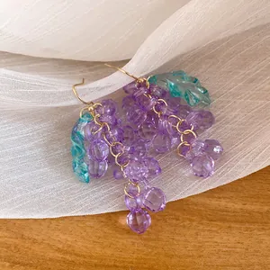 Macro shot showcasing the intricate purple faceted acrylic grape cluster earrings with a teal leaf