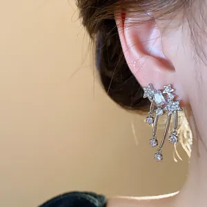 Dettaglio ravvicinato di eleganti orecchini a stella cadente in zircone sull'orecchio di modella