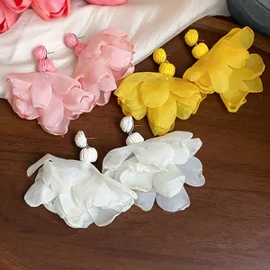Close-up detail of bohemian style chiffon flower earrings in soft pink, vibrant yellow and white